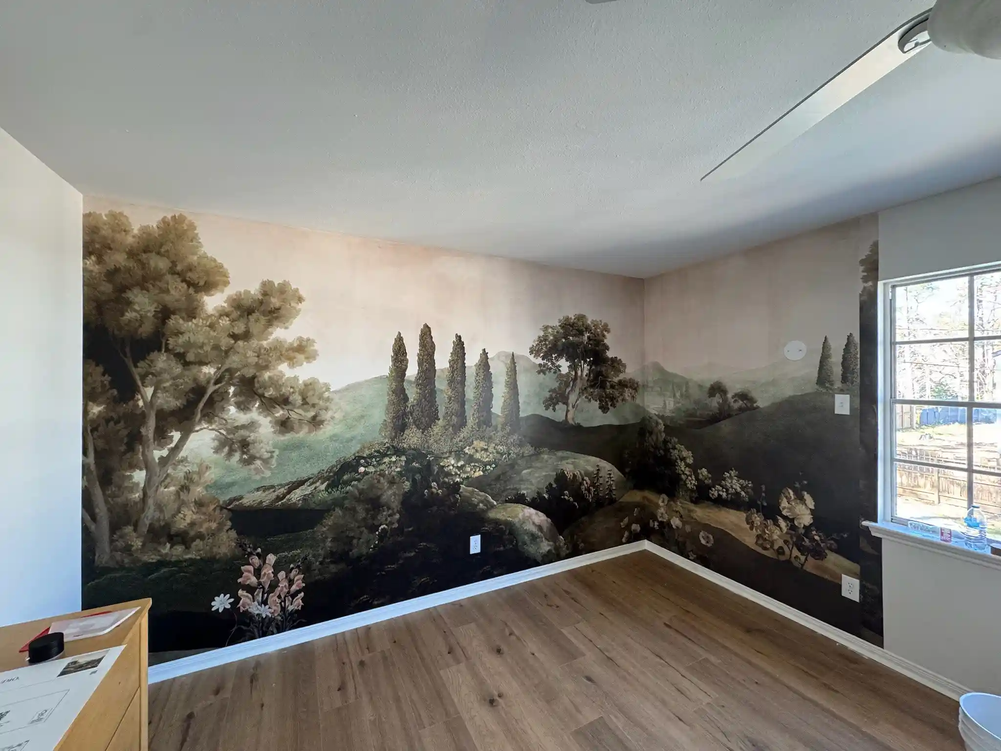 Landscape mural wallpaper spanning two walls in a bright room